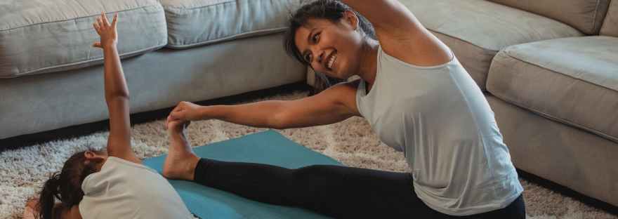 cheerful asian mother and daughter stretching body in living room