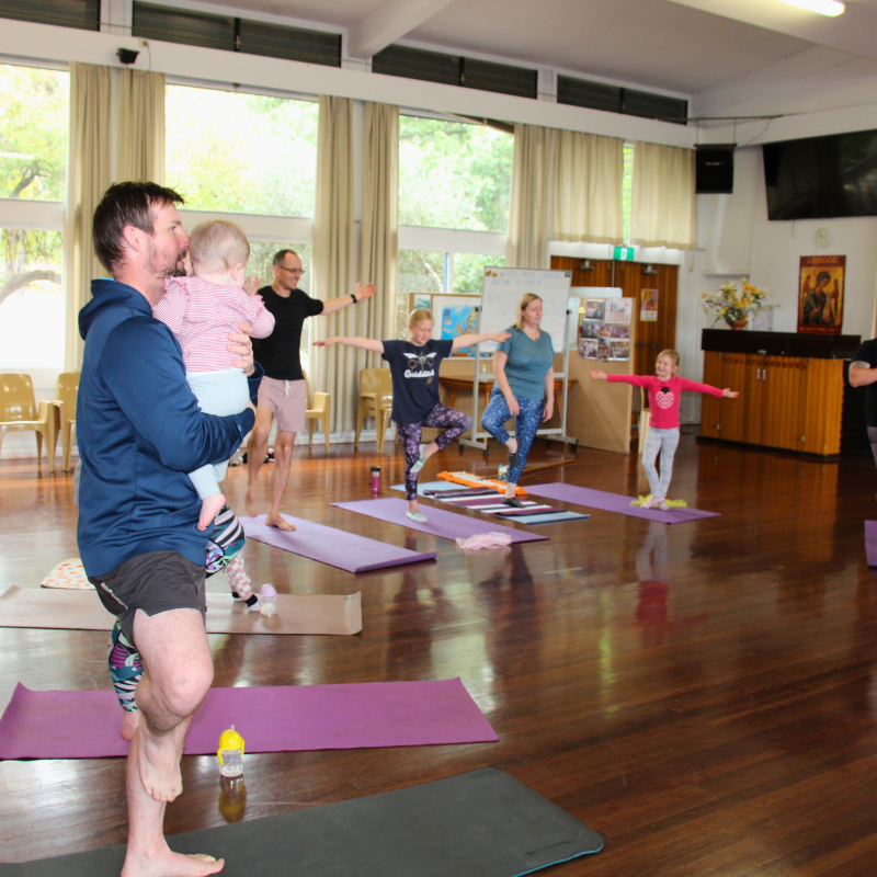 A family enjoying yoga at Shine Om'ss free community to celebrate ACT Children's Week in Canberra. Visit shineom.com.au/familyyoga to explore classes near you.
