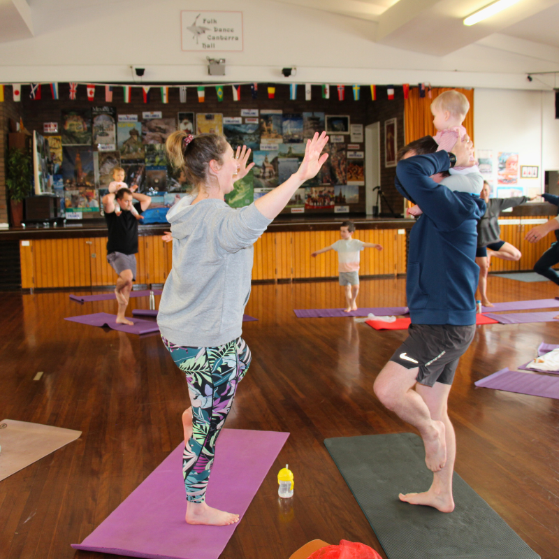 A family enjoying yoga at Shine Om'ss free community to celebrate ACT Children's Week in Canberra. Visit shineom.com.au/familyyoga to explore classes near you.