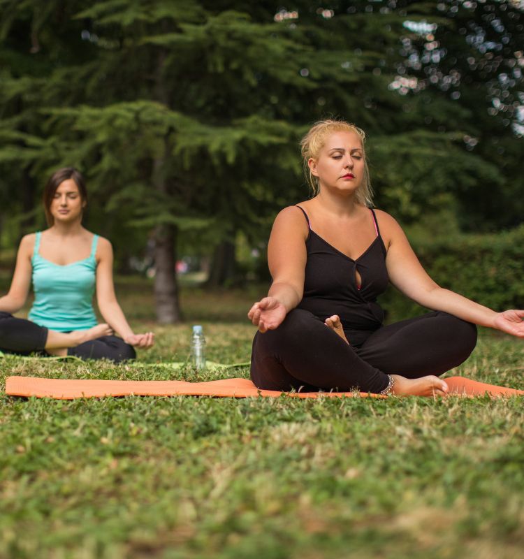 A couple of mums sitting on their yoga mats with eyes closed and mid-exhale. Learn how parents and mums can use their breath to connect with calm at www.shineom.com.au