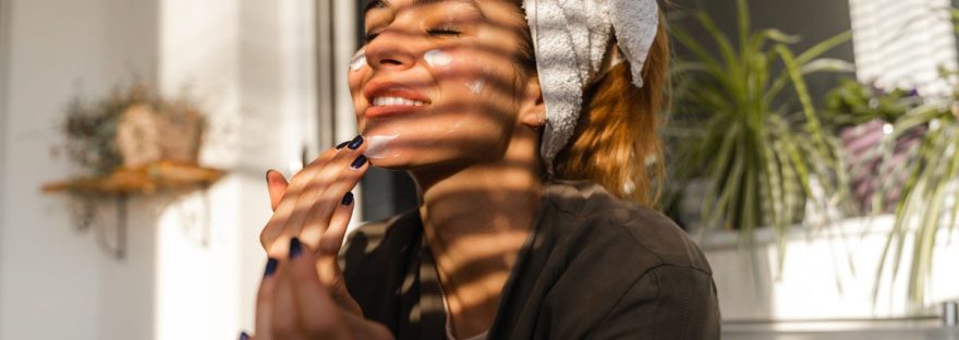 Mother practicing self-care by gently applying natural facial cream, creating a mindful moment amidst the busyness of parenting. Read more at www.shineom.com.au/articles