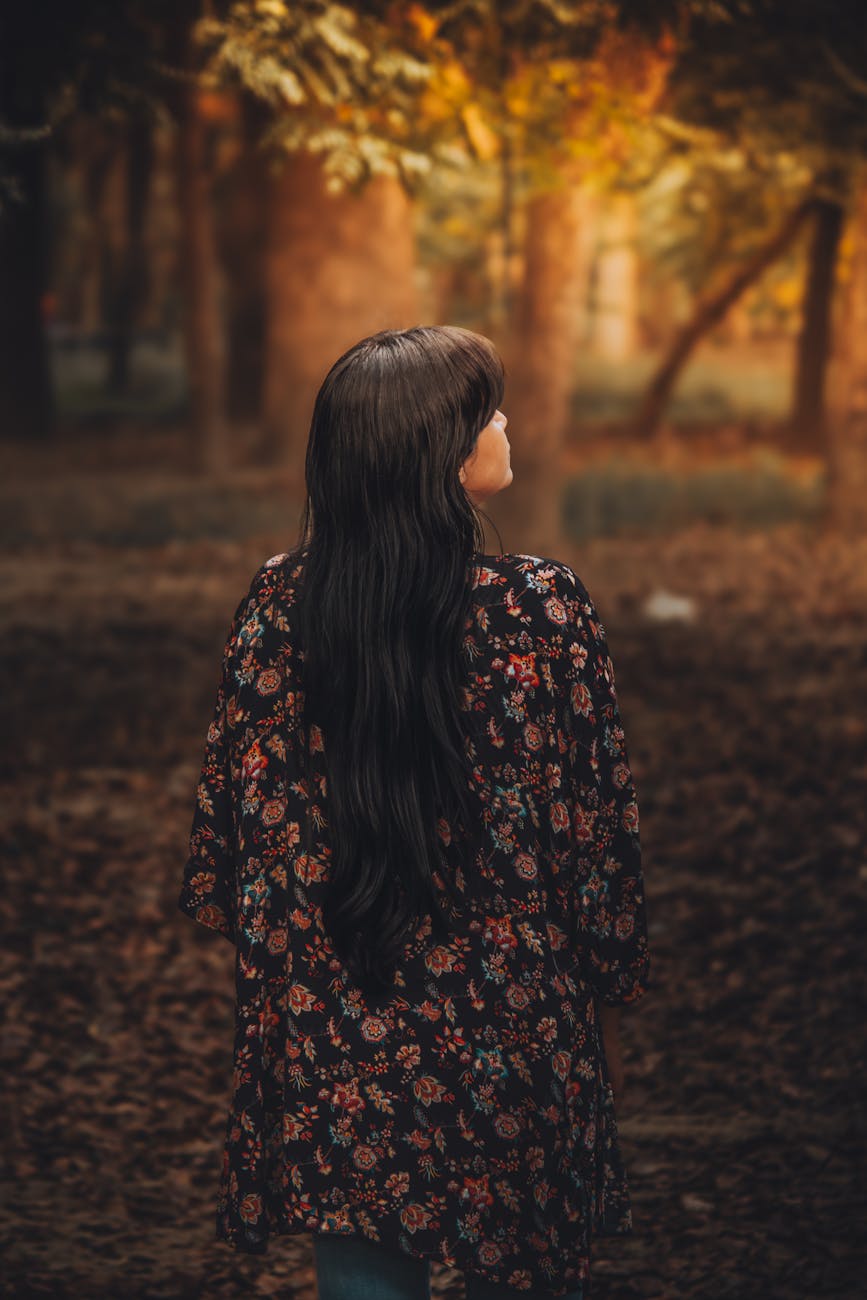 woman with long hair strolling in autumn forest, quietly in nature during a liminal season of life, symbolising transition, becoming and inner trust