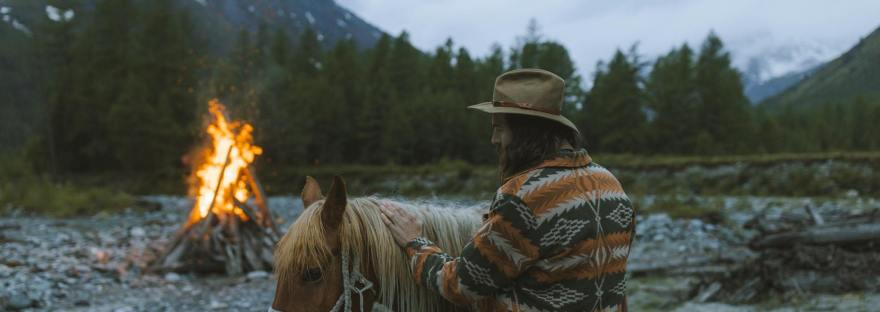 a man in printed long sleeves touching a horse reflecting on the energies of 2026 with calm and intention